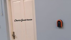 A white door with the text "Charis Guest house" on it.