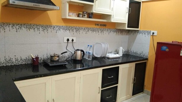 A kitchen with a black countertop, white cabinets, and a red refrigerator.