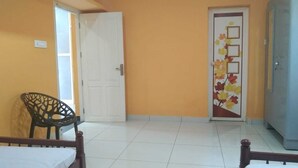 A room with a white door, a chair, and a bed.