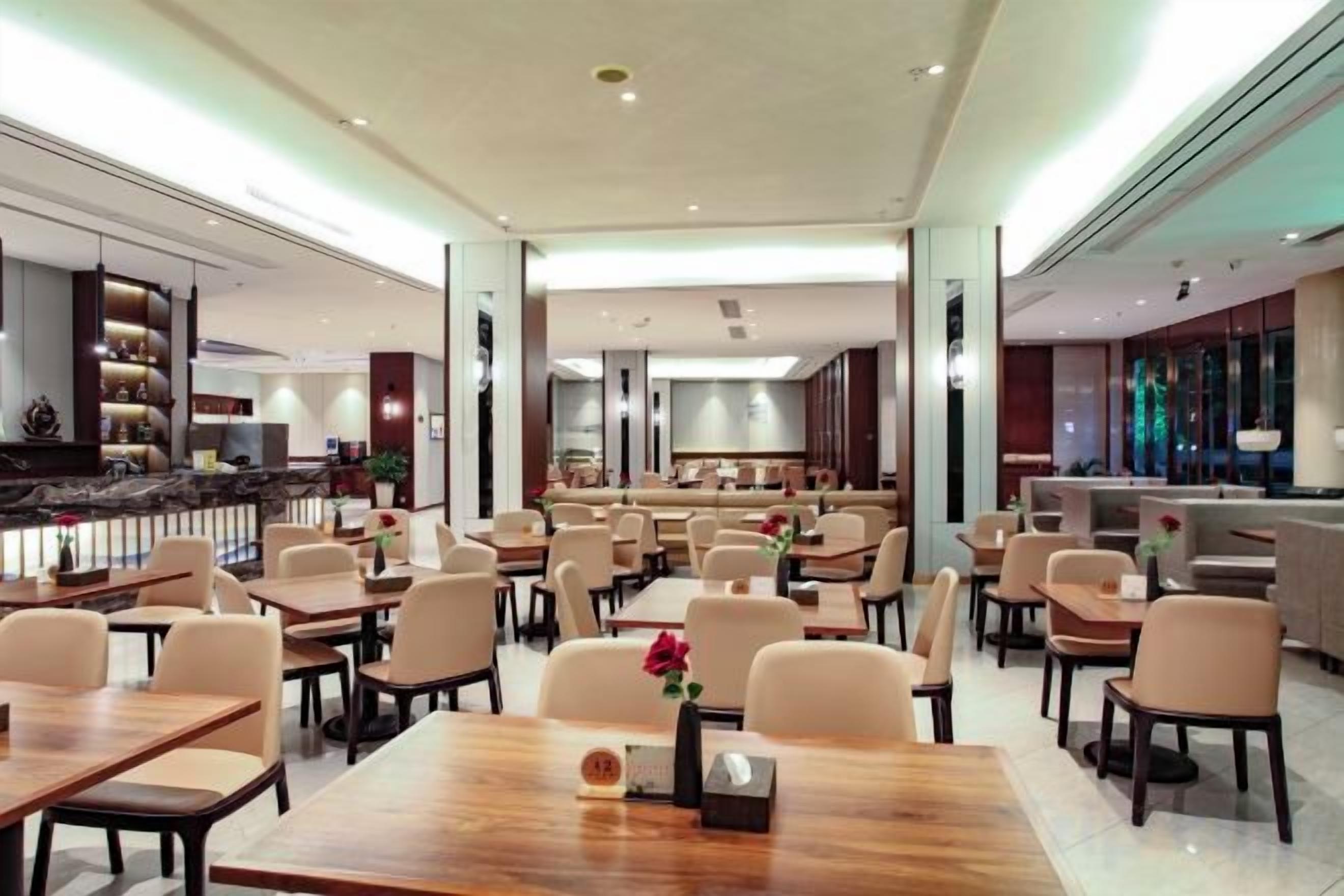 Un restaurante espacioso con varias mesas y sillas, una zona de bar y una decoración de diseño moderno.