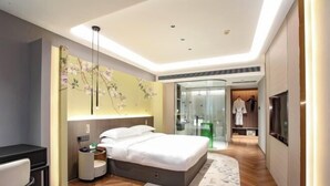 A modern hotel room with a bed, bedside table, and a large mirror.