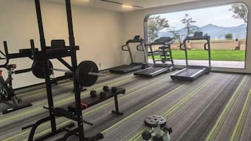 A gym with cardio equipment, weightlifting stations, and a view of the outdoors.
