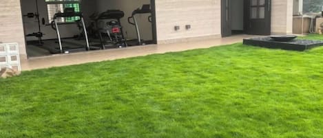 Una casa con un césped cuidado, un garaje con equipo de ejercicio y una puerta que da al garaje.