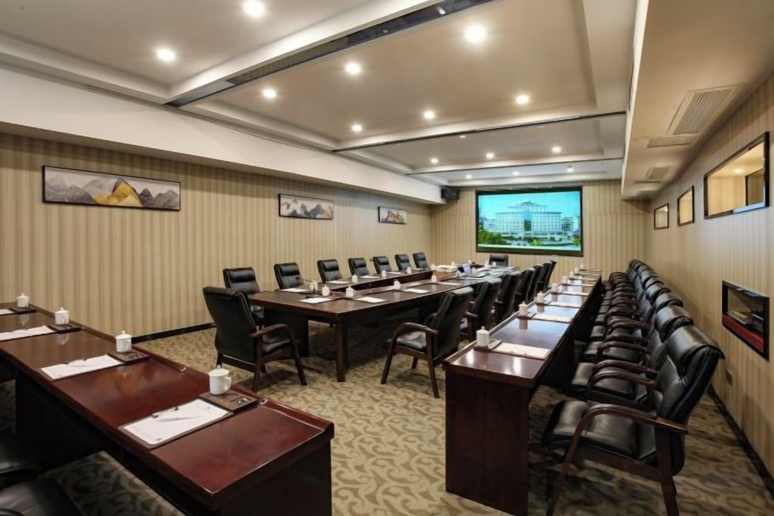 Ein Konferenzraum mit langem Tisch, mehreren Stühlen und einer Projektionsleinwand.