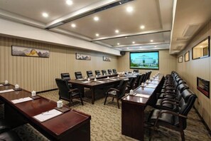 A conference room with a long table, multiple chairs, and a projector screen.
