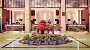 A lobby with reception desks, a large decorative lion statue, and potted plants.