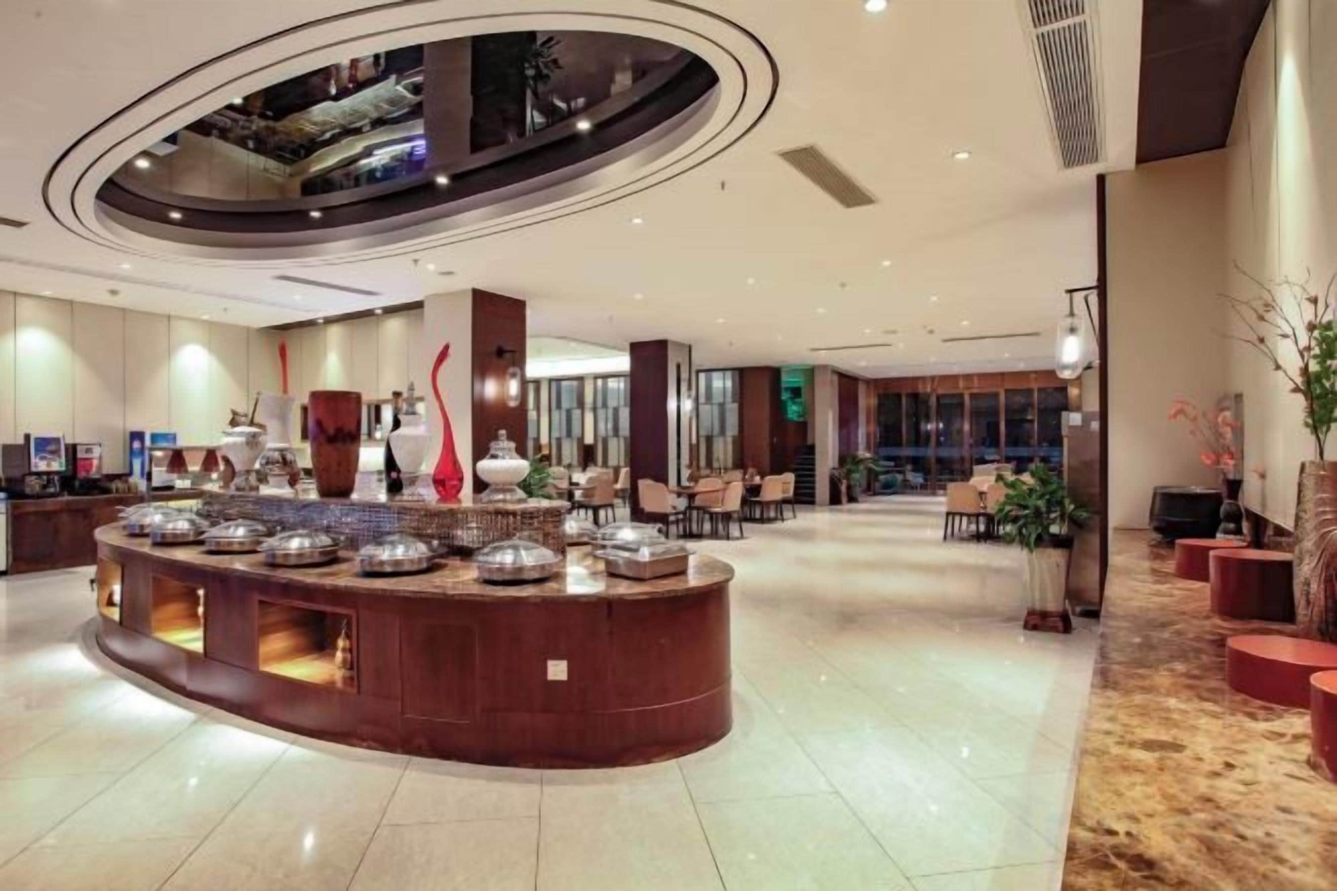 Hall d'albergo con reception centrale, zona salotto e ampia finestra.