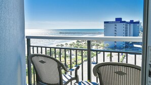 A balcony with two chairs, a view of the beach, a pier, and a building labeled "North" in the background. - Oceanfront Condo Gorgeous View&Pools (Myrtle Beach)