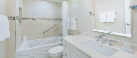 A modern bathroom with a bathtub, toilet, and vanity.