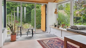 A modern interior with a large sliding glass door leading to a garden, a wooden ceiling, and a bench with cushions. - 5 Star Holiday Home in Nakskov (Nakskov)
