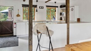 A modern kitchen with white cabinets, a wooden beam ceiling, and a rustic door. - 5 Star Holiday Home in Nakskov (Nakskov)
