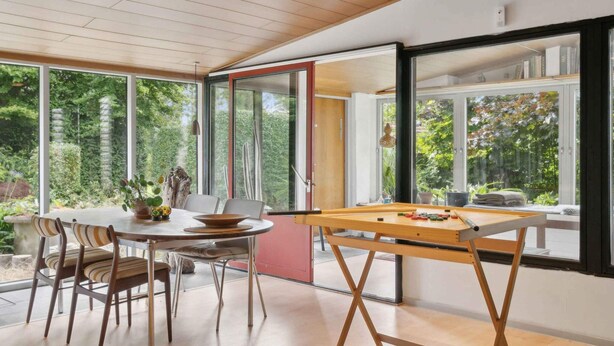 A modern dining area with a pool table, dining chairs, and large windows offering a view of the outdoors. - 5 Star Holiday Home in Nakskov (Nakskov)