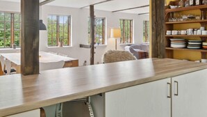 A kitchen with wooden beams, a dining area with a table and chairs, and a view of greenery outside. - 5 Star Holiday Home in Nakskov (Nakskov)