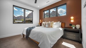 A bedroom with a large bed, two bedside tables, a nightstand, and a view of mountains through the windows. - Montclair Zion - a Stunning Luxury Villa, 2 Bed, 1 Bath Retreat with Balcony (Springdale)