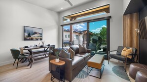 A modern living room with a sofa, coffee table, and chairs, a dining area with a table and chairs, and large windows offering a view of the outdoors. - Montclair Zion - a Stunning Luxury Villa, 2 Bed, 1 Bath Retreat with Balcony (Springdale)