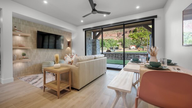 Una sala de estar moderna con un sofá, una mesa de comedor y un televisor montado en la pared.