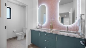 Un baño moderno con inodoro, lavabo y espejo.