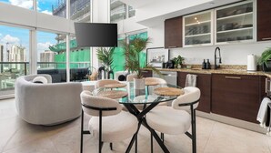 Una cucina moderna con mobili scuri, un tavolo da pranzo in vetro e vista sulla città.