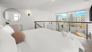 Una camera da letto moderna con un grande letto, uno specchio rotondo e un balcone con vista sulla città.
