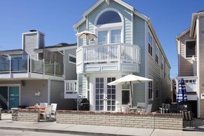 A two-story house with a balcony, a grill outside, and a sign for rent.