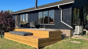 Uma casa moderna com um amplo deck, móveis de exterior e uma chaminé.