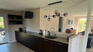 Cozinha moderna com armários escuros, uma ilha grande com pia e luminária pendente.