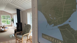 Um quarto acolhedor com uma janela grande, soalho de madeira, lareira preta e um mapa de Karrebæksminde.