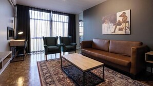A modern living room with a sofa, two armchairs, a coffee table, and a TV. - Hotel 224 & Apartments (Pretoria)