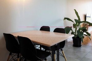 Una sala de conferències amb una taula rectangular, quatre cadires i una planta en test.