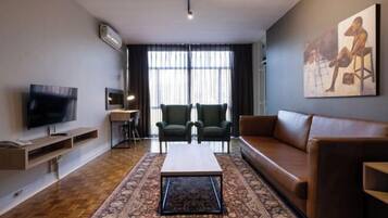 A modern living room with a flat-screen TV, a sofa, a coffee table, and a patterned rug.