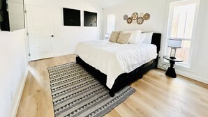 A bedroom with a bed, a ceiling fan, a bedside table, a rug, and a window.