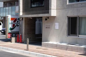 A building with a 7-Eleven store on the ground floor, a concrete facade, and a window with a metal frame. - Poka Stay Kamata (Tokyo)