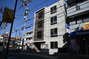 A multi-story building with commercial signage, including a Panasonic store. - Poka Stay Kamata (Tokyo)