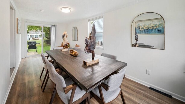 A dining area with a wooden table, six chairs, and a large window. - Group Ready 4BR near OSU w/ Fire Pit & Wet Bar (Columbus)