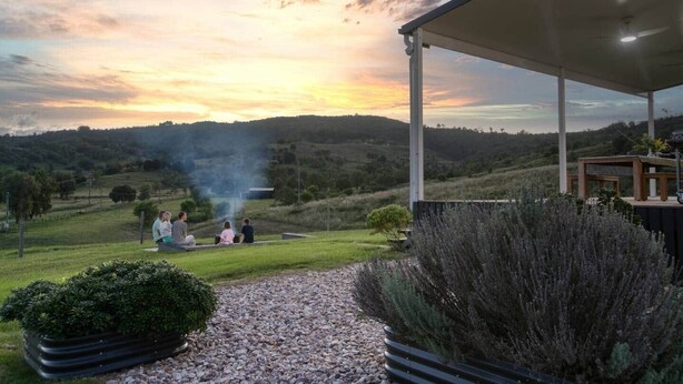 Un espace extérieur abrité, aménagé avec des sièges, d’où l’on peut admirer un coucher de soleil sur des collines ondoyantes.