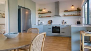 Une cuisine moderne dotée d’un îlot central, d’appareils électroménagers intégrés et d’un coin repas avec une table et des chaises en bois.