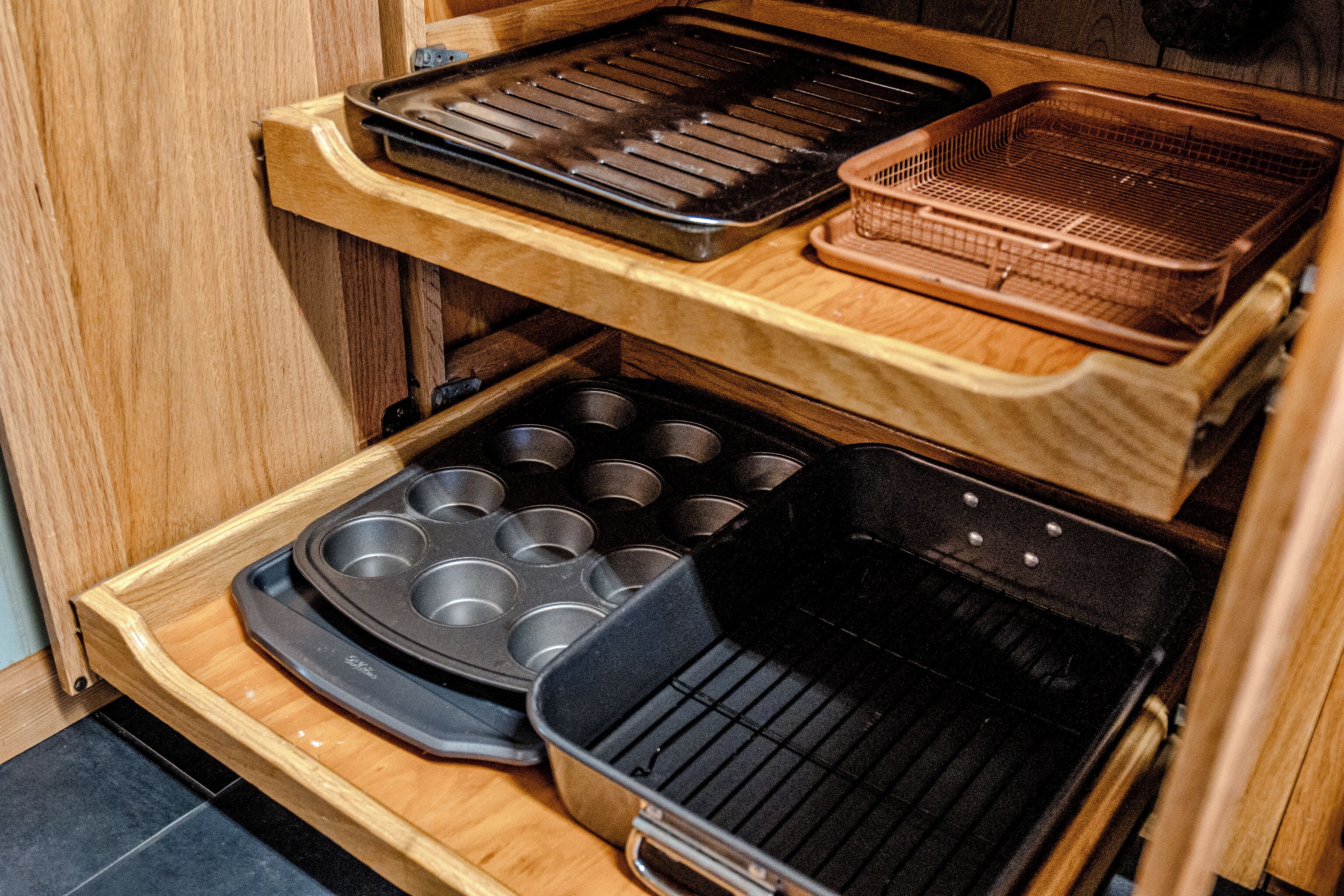 A kitchen with a wooden countertop, a muffin tray, a griddle, and a wire basket.