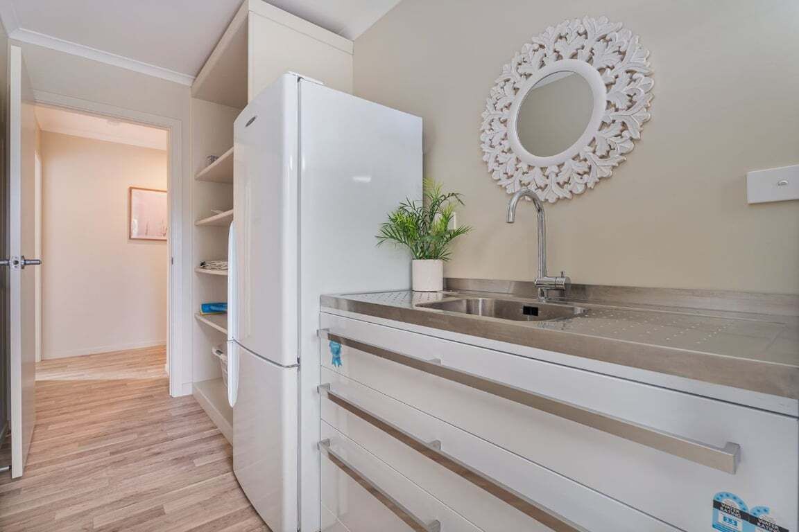 A kitchen with a white refrigerator, a sink, and a decorative mirror on the wall.