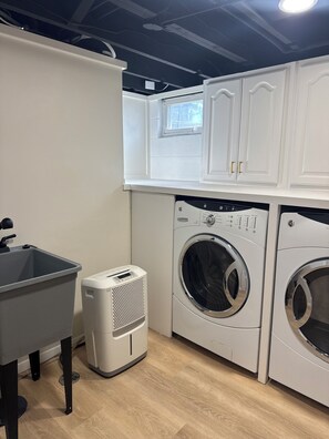 Una sala de lavandería con lavadora, secadora y lavabo.