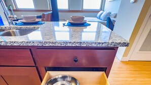 A kitchen with granite countertops, a wooden floor, and a drawer containing two metal bowls. - River Views and FREE Parking! (Saint Paul)