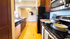 A modern kitchen with wooden cabinets, stainless steel appliances, and a wooden floor. - River Views and FREE Parking! (Saint Paul)
