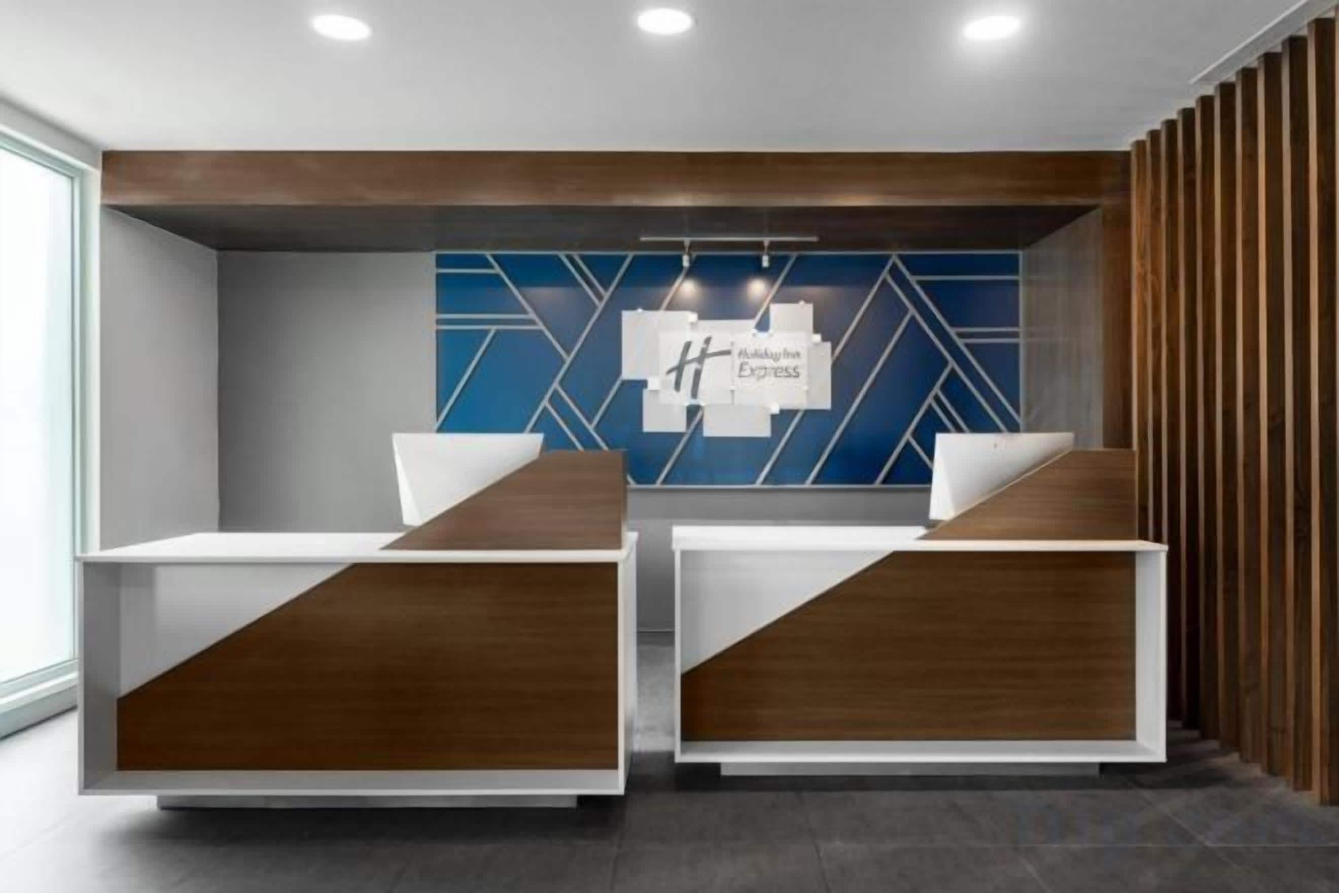 Un espace d’accueil doté de deux comptoirs de réception, d’un mur orné de motifs géométriques bleus et d’un panneau décoratif en bois.