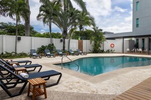Zona junto a la piscina con sillones de descanso y una piscina.
