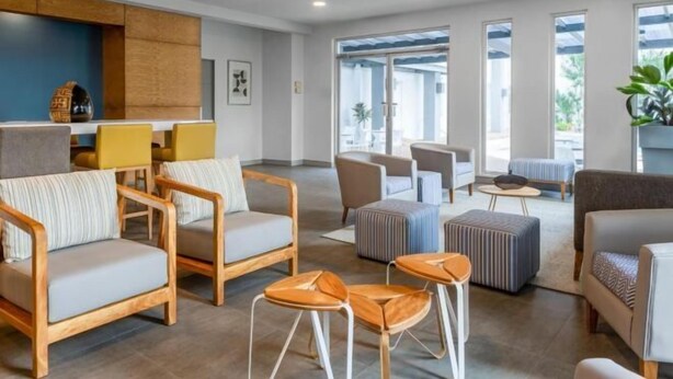 En modern hotellobby med trämöbler, en blå accentvägg och stora fönster.