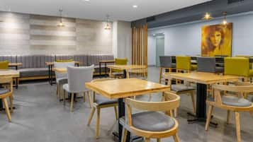 A modern dining area with booths and tables, wooden chairs, and pendant lighting.