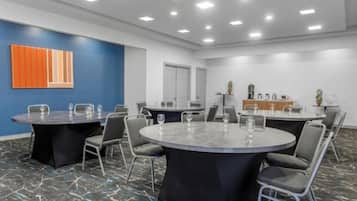 A conference room with round tables, chairs, and a blue accent wall.