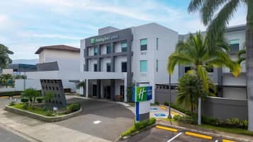 A modern hotel with a flat roof, a parking lot, and a sign indicating handicap accessibility.