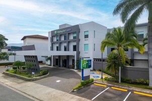 Un hotel moderno con techo plano, estacionamiento y señal de accesibilidad para personas con discapacidad.