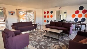 A living room with two sofas, a coffee table, and a dining area with chairs and a table.