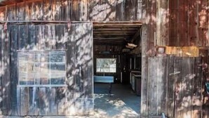 A rustic barn with a large open door leading to a spacious interior.